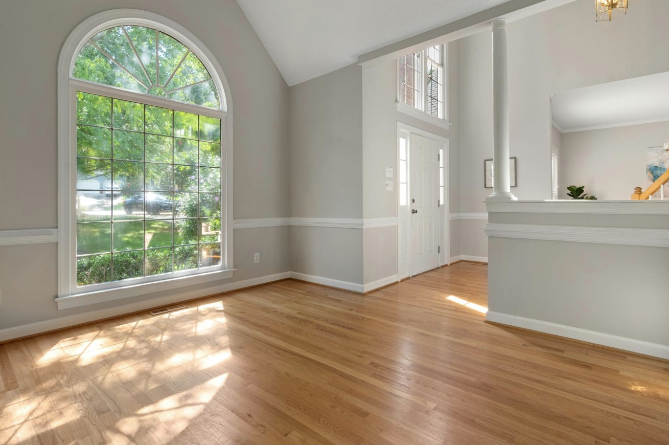 An image from McKinney Hardwood Flooring's website that depicts a natural hardwood floor installed in a living room and entryway of a home.